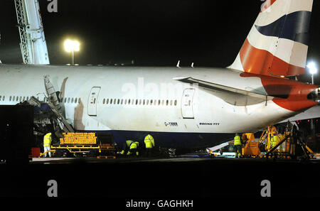 L'avion Boeing 777 de British Airways, qui a atterri à Heathrow hier après-midi, est maintenu au large du sol par deux grues géantes, alors que les travailleurs tentent de supporter le train roulant avec des blocs de bois, ce soir. Banque D'Images