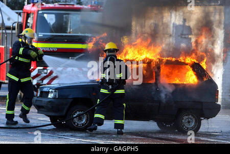 Certains des dix-huit nouveaux pompiers stagiaires s'attaquent à un incendie lors d'une cérémonie de remise des diplômes au centre de formation aux services d'incendie et de sauvetage de Belfast, qui a terminé leur cours de formation de 12 semaines et se joindra à des collègues de toute l'Irlande du Nord. Banque D'Images
