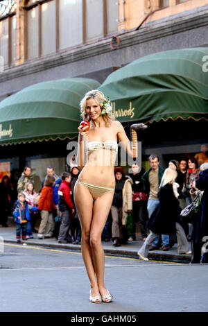 La mannequin Louise Dainton pose pour les photographes et les amateurs de shopping à Harrods à Knightsbridge, dans le centre de Londres, après avoir été peinte à la main comme un serpent par l'artiste Guido Daniele. Banque D'Images