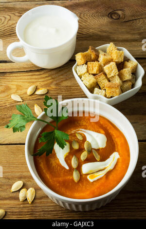 Crème de Courge potiron à la crème et les graines de citrouille dans le bol, blanc crème dans une bouteille et les croûtons dans une assiette de service sur t Banque D'Images