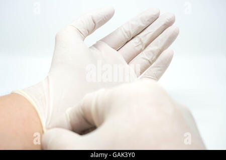 Mettre des gants à usage unique stérile, blanche sur fond blanc Banque D'Images