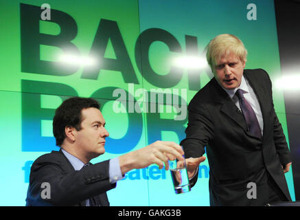 Le chancelier de l'ombre George Osborne donne un verre d'eau au candidat conservateur du maire de Londres Boris Johnson alors qu'il se prépare à faire un discours sur l'économie de Londres dans les bureaux de Bloomberg dans la City de Londres, avant le budget de cette semaine. Banque D'Images