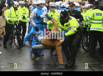 Un policier lutte contre un manifestant au sol après qu'il a attrapé et tenté de prendre la torche olympique de la présentatrice de télévision britannique Konnie Huq (non vu) pendant une partie de son voyage à travers Londres sur son chemin à l'éclairage du chaudron olympique à l'O2 Arena de Greenwich. Banque D'Images