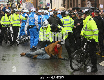 Un policier lutte contre un manifestant au sol après qu'il a attrapé et tenté de prendre la torche olympique de la présentatrice de télévision britannique Konnie Huq (non vu) pendant une partie de son voyage à travers Londres sur son chemin à l'éclairage du chaudron olympique à l'O2 Arena de Greenwich. Banque D'Images