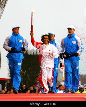 L'athlète britannique Dame Kelly Holmes court avec la torche olympique tenue en altitude après avoir terminé la dernière partie du relais de la torche olympique à l'O2 Arena. Banque D'Images