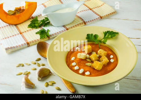 Courge potiron rôti à la crème soupe aux légumes, graines de potiron, croûtons à l'ail et le persil dans une plaque jaune sur blanc wo Banque D'Images