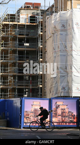 Un cycliste passe une entrée pour les véhicules de construction à Imperial Wharf, un développement mixte de St George PLC (faisant partie de Berkeley Group Holdings) sur les rives de la Tamise à côté de Chelsea Harbour. Banque D'Images