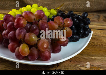 Bouquet de blanc, rouge et raisins noirs sur un fond de bois sombre. Grappe de raisin. Grappe de raisins. Les raisins de Custer. Les raisins de Banque D'Images