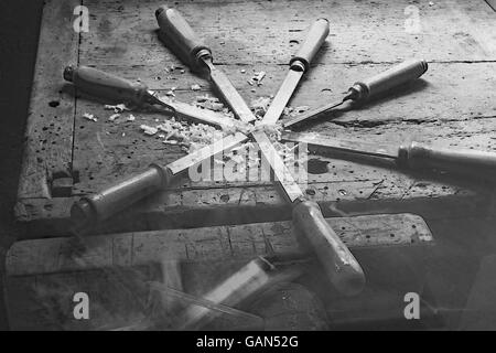 Série de plusieurs lames en acier forte de nombreux burins et sciures humides dans Workbench en noir et blanc Banque D'Images