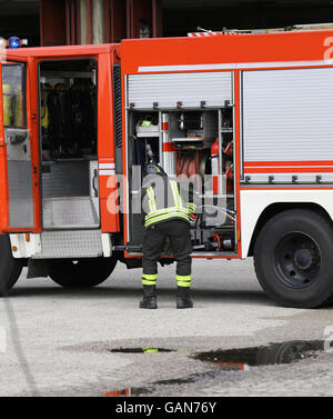 Prépare les tuyaux de l'eau pompier pour éteindre l'incendie pendant un exercice dans la station de pompiers Banque D'Images