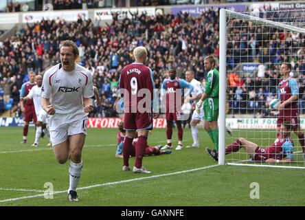 Kevin Davies, de Bolton Wanderers, célèbre après avoir atteint le but d'ouverture Alors que les joueurs de Ham de l'Ouest se tiennent abattu dans le arrière-plan Banque D'Images