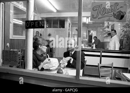 La pop star Phil Collins achète l'actrice Julie Walters un repas à emporter de poisson et de frites dans un café du sud de Londres lors de la première journée de tournage de Buster, un film sur le plus grand « à emporter » des années 1960, le « Grand vol de train ». Banque D'Images