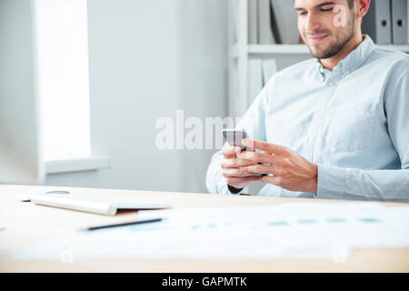 Portrait d'un homme assis à la table et l'utilisation de smartphone à l'office de tourisme Banque D'Images