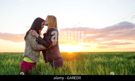 Blonde girl kissing et son joli sourire meilleurs amis à l'extérieur. Banque D'Images