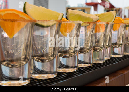 Peu de verres transparents en ligne avec les tranches d'Orange et de Lime prêt à Tequila Shots Banque D'Images