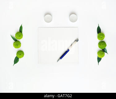 Papier, stylo et des bougies avec décoration de fleurs de chrysanthèmes et de ficus feuilles sur fond blanc. Vue de dessus. Mise à plat. Banque D'Images