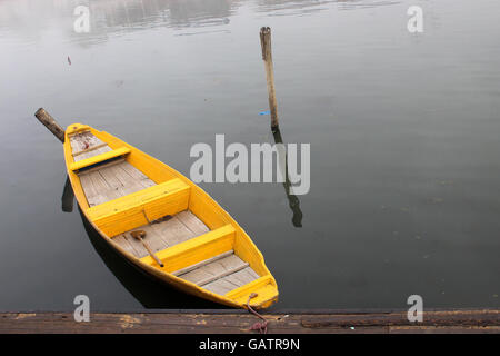 Bateau à rames sur le lac. Bateau à rames jaune, tôt le matin, avec un peu de brouillard sur l'eau. Voile sur le lac Dal au Cachemire, en Inde. Banque D'Images