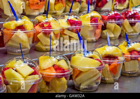 Cocktail de fruits frais salade dans des gobelets en plastique sur un étal du marché Banque D'Images