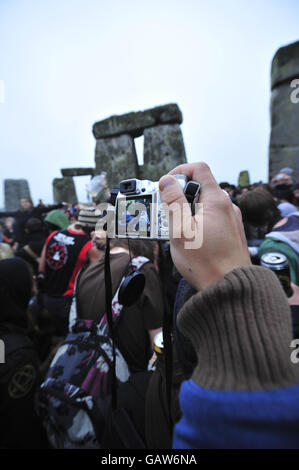 Les gens prennent des photos à l'intérieur du cercle de pierre à l'aube, car le mauvais temps et la pluie empêchent le soleil de briller le matin du solstice d'été à Stonehenge, Wiltshire. Banque D'Images
