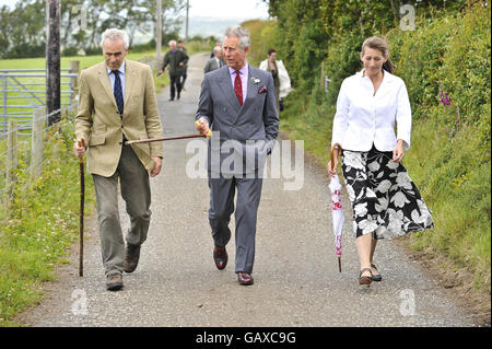 Le Prince de Galles (au centre) marche avec les propriétaires de la ferme de Bwlchwernen Fawr Patrick Holden (à gauche) et sa femme Becky Holden (à droite) en bas de la voie vers la ferme de Llangybi, Lampeter, pays de Galles. Banque D'Images