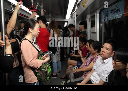 Le peuple chinois de Guangzhou train ride de métro, certains assis d'un certain rang, certains jouent avec leurs smartphones. Guangzhou, Chine. Banque D'Images