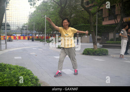 Une vieille femme chinoise à la retraite sourit comme elle le tai chi tôt le matin dans un parc public. Kowloon, Hong Kong. 06.05.2016. Banque D'Images