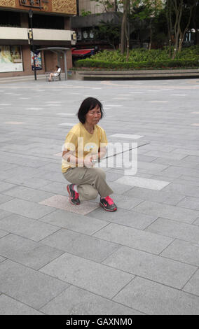 Une vieille femme chinoise à la retraite est très intense et se concentrer comme elle le fait le Tai Chi dans un parc public à l'aide d'une lance ou une épée. Kowloon, Hong Kong. Banque D'Images