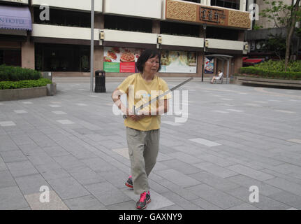 Une vieille femme chinoise à la retraite est très concentré à l'aide d'une épée intensly comme elle ne le Tai Chi dans un parc public à l'aide d'une lance. Kowloon, Hong Kong. Banque D'Images