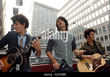 (De gauche à droite) Nick, Joe et Kevin Jonas des Jonas Brothers exécutent un concert acoustique dans un bus à toit ouvert dans le centre de Londres. Banque D'Images