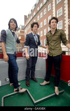 (De gauche à droite) Joe, Nick et Kevin Jonas des Jonas Brothers posent dans un bus à toit ouvert dans le centre de Londres. Banque D'Images