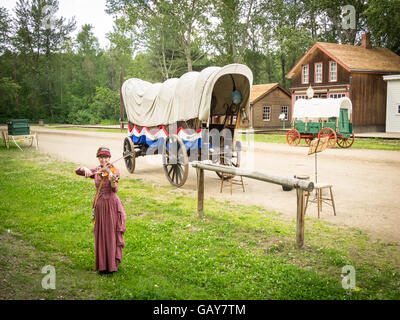 Un violoneux en costume joue en face d'un wagon couvert sur la rue '1885' au parc du Fort Edmonton à Edmonton, Canada. Banque D'Images