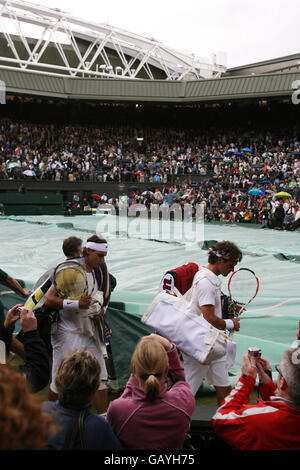 Rafael Nadal en Espagne et Roger Federer en Suisse quittent Center court car les couvertures sont tirées en raison de la pluie lors des championnats de Wimbledon 2008 au All England tennis Club de Wimbledon. Banque D'Images