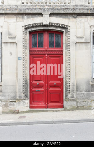 Double portes en bois rouge à l'entrée d'un ancien bâtiment en pierre en France Banque D'Images