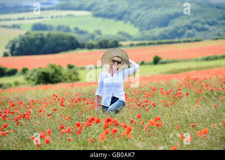 Belle femme marcher parmi des champs de pavot près de Ditchling Beacon Sussex UK Banque D'Images
