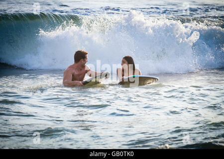 Jeune femme et l'homme en attente de vague de rouler sur du boogie board Banque D'Images