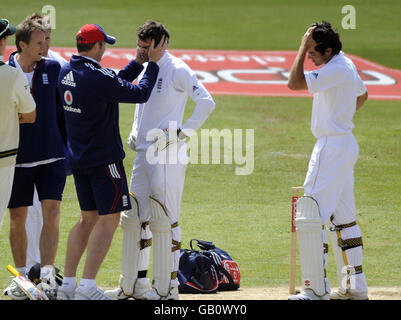 Le batteur d'Angleterre James Anderson reçoit un traitement alors qu'il est surveillé par son partenaire de baseball Alastair Cook (à droite) après avoir été frappé à la tête d'une balle au large de l'Bowler sud-africain Dale Steyn lors du deuxième match de npower Test au terrain de cricket de Headingley, à Leeds. Banque D'Images