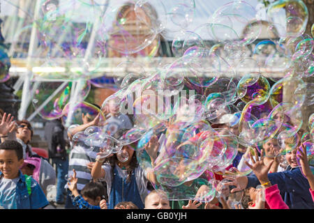 Les enfants d'essayer de suivre les grandes bulles à Southbank, Londres en Juillet Banque D'Images