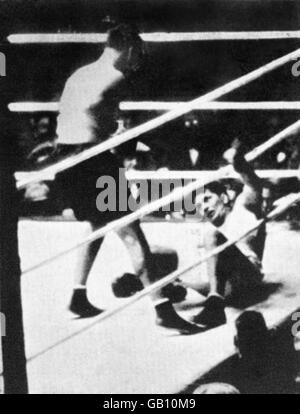 Gene Tunney (r), champion de poids lourd, regarde depuis la toile après avoir été lancé par un tir de Jack Dempsey (l), challenger, au septième tour. Tunney aurait séjourné pendant 14 secondes comme arbitre Dave Barry a passé cinq secondes à persuader Dempsey de se retirer dans un coin neutre avant de commencer son décompte. Tunney a récupéré pour gagner des points, mais sa victoire a été mise à l'ombre par la controverse du « long Comte » Banque D'Images