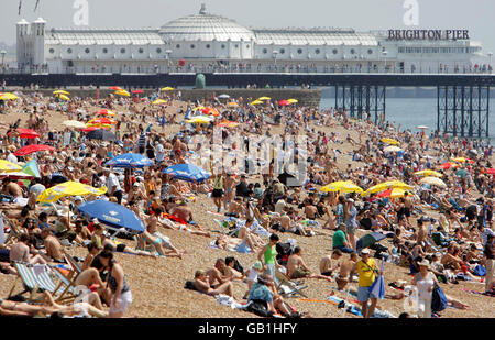 Les amateurs de plage apprécient le temps chaud sur le front de mer de Brighton. Banque D'Images