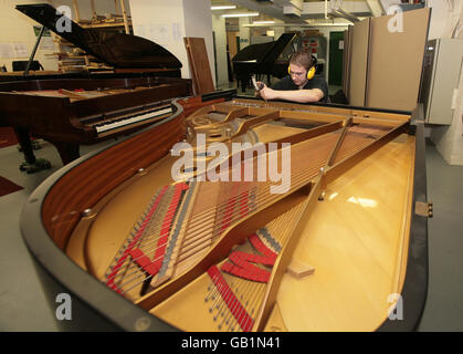 Peter Dzilinski, technicien stagiaire, répare un piano au centre de restauration Steinway, dans le centre de Londres. Le Steinway Hall, qui a ouvert ses portes en 1875, est situé à quelques minutes de l'agitation d'Oxford Street. Banque D'Images