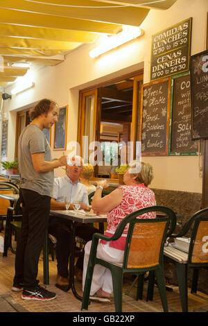 Afin de Waiter taking un couple de personnes âgées dans un restaurant, Puerto Pollensa, Mallorca ( Majorque ), Îles Baléares Espagne Europe Banque D'Images