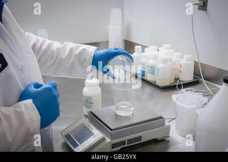 Les mains du technicien de laboratoire en produits chimiques de verser dans le bécher de mesure pesage Banque D'Images