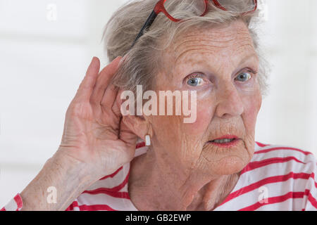 Mature Woman holding part à l'oreille Banque D'Images