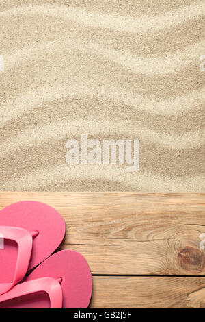 Concept d'été rose avec des tongs sur la plage de sable Banque D'Images
