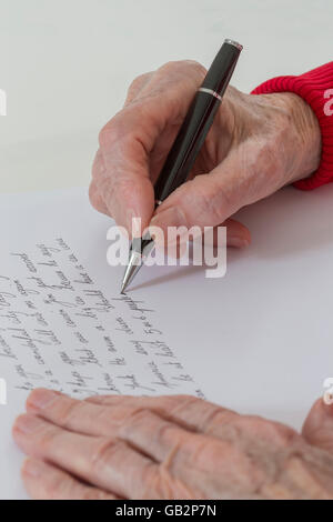 Portrait of senior woman sitting at desk et l'écriture. Banque D'Images