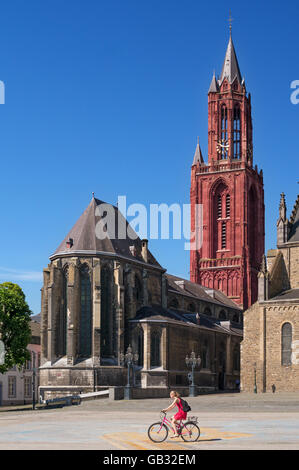 Jeune femme en robe rouge le vélo voyage het Vrijthof carré avant de l'église Saint John's, Maastricht, Pays-Bas, Europe Banque D'Images