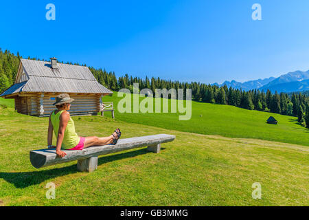 Jeune touriste assis sur banc en bois sur pré vert et à la recherche à Tatras, Pologne