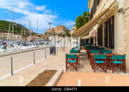 PORT DE BONIFACIO, CORSE - 25 juin 2015 : : restaurant à Bonifacio port avec la construction de la citadelle en arrière-plan. Bonifacio a f Banque D'Images