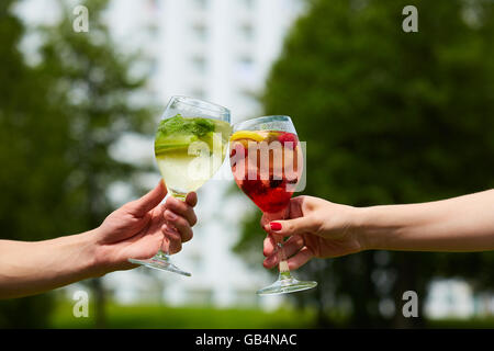 Hand holding cocktail verres trinquer ensemble à l'extérieur. Banque D'Images