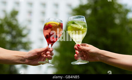 Hand holding cocktail verres trinquer ensemble à l'extérieur. Banque D'Images